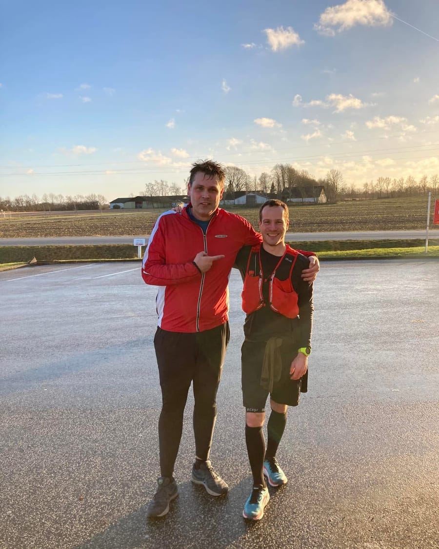 David løber sammen med en træningsmakker ad en landevej i aftenlys.