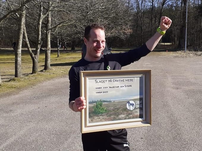 David med hævet arm og et indrammet diplom efter sejren.