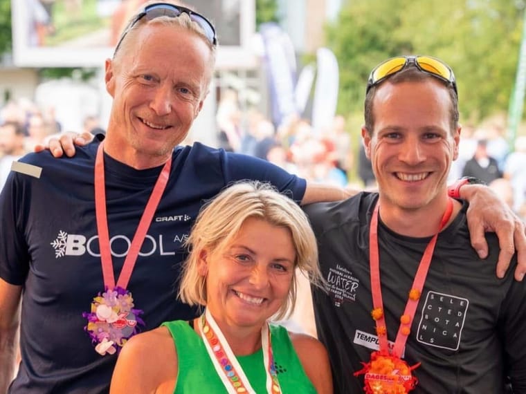 Tre løbere med medaljer om halsen foran publikum.